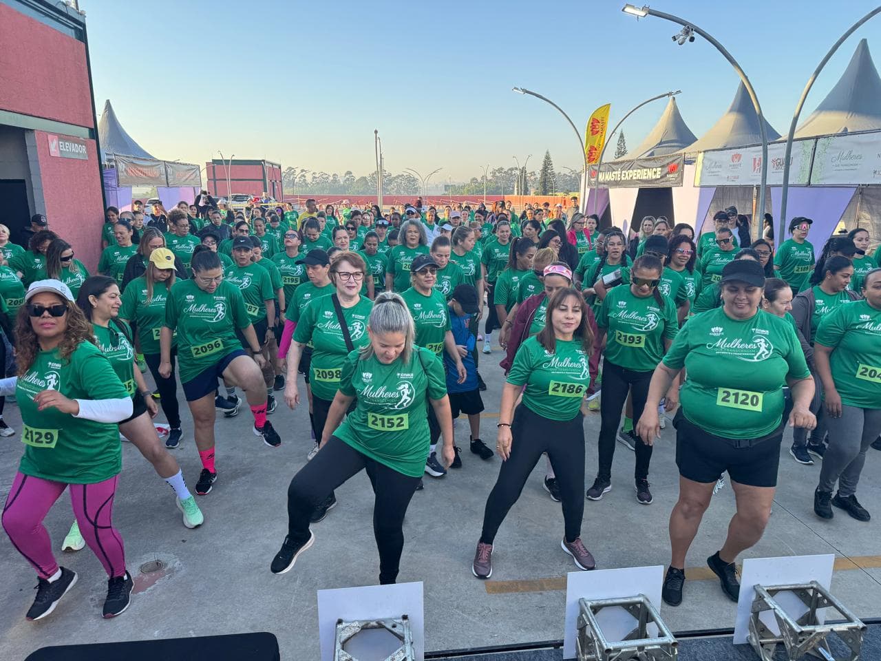 Participantes da Corrida Mulheres que Transcendem durante o aquecimento antes da largada